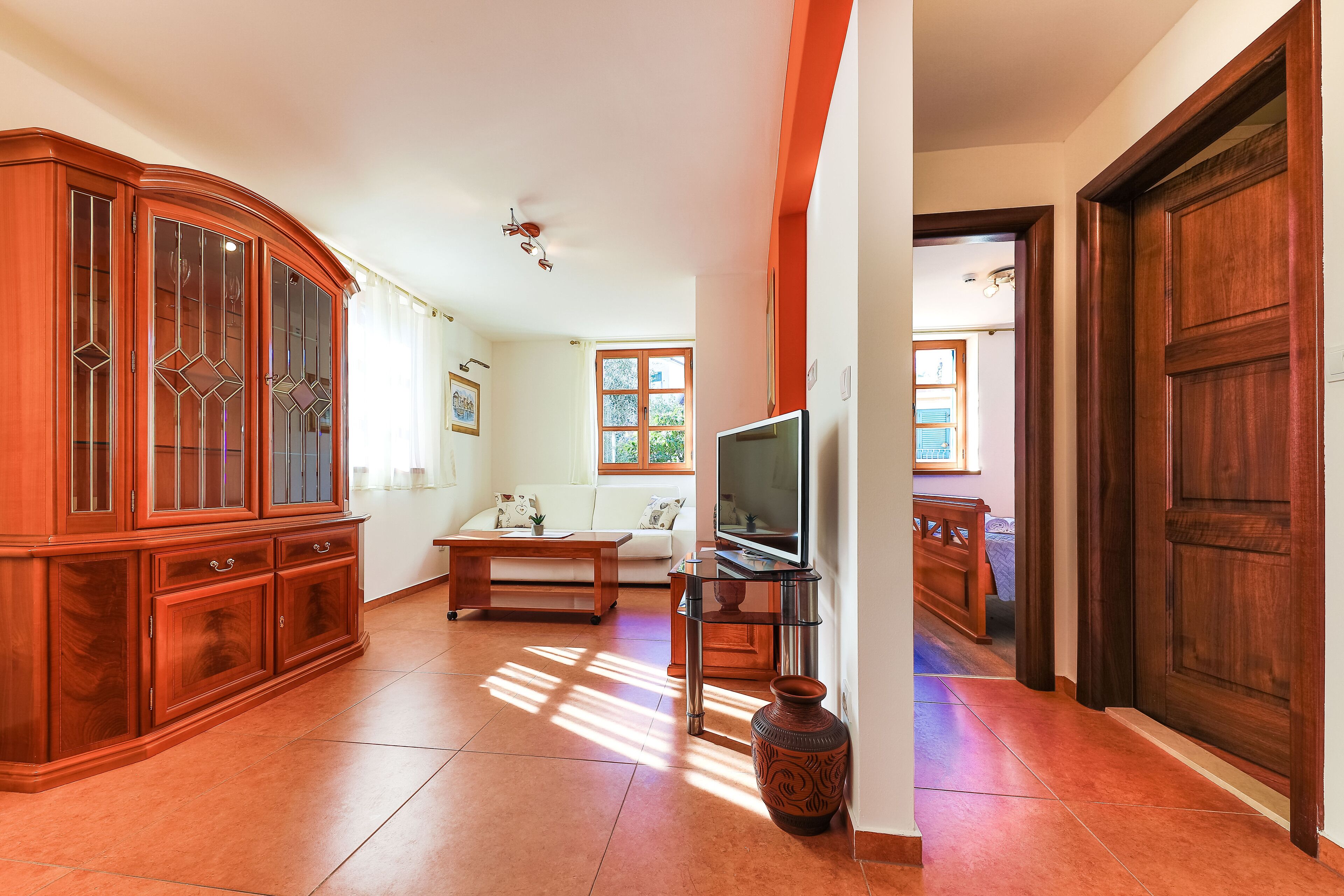 A spacious living room with a wooden cabinet, a sofa, a coffee table, and a television.