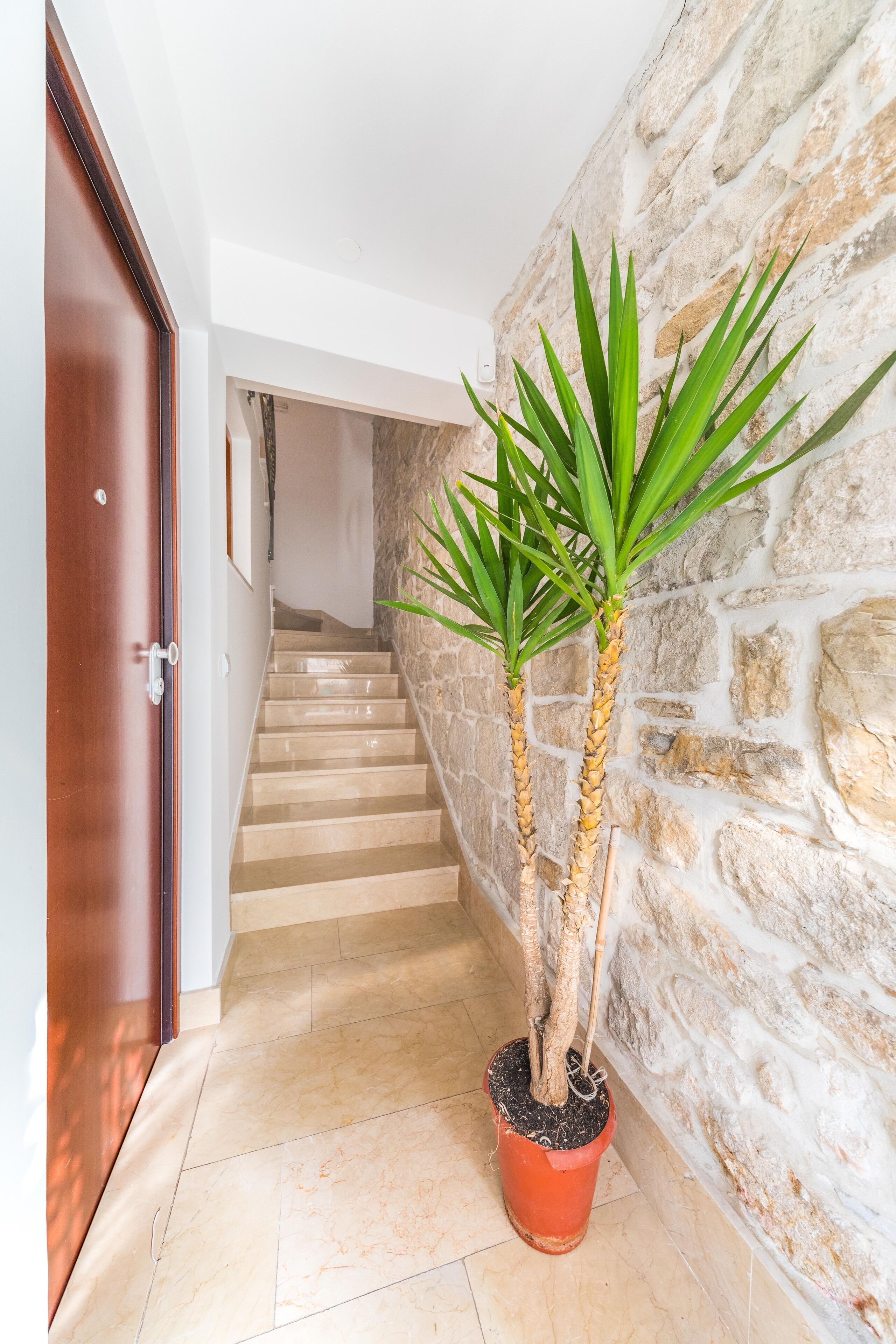 Un couloir avec un mur en pierre, une porte en bois et un escalier.