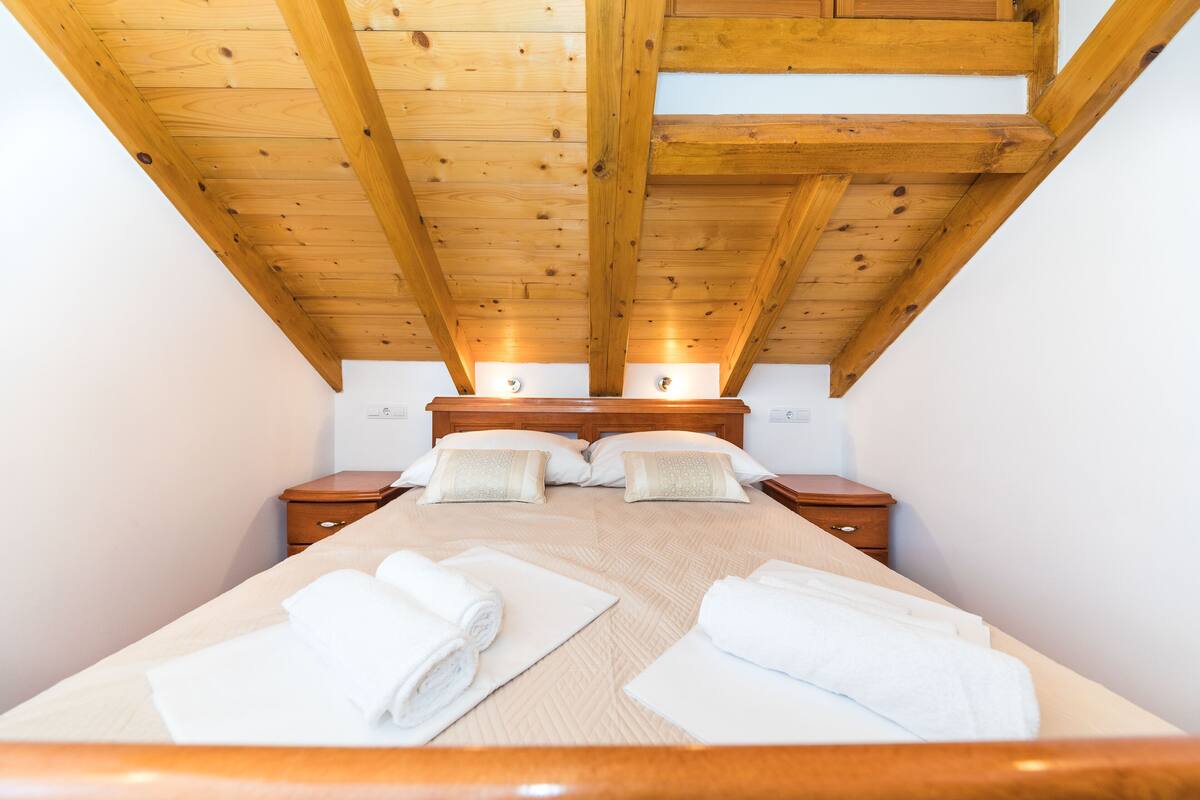 Ein Schlafzimmer mit Holzboden, einem Bett mit weißer Bettwäsche, zwei Nachttischen und einem beibett.