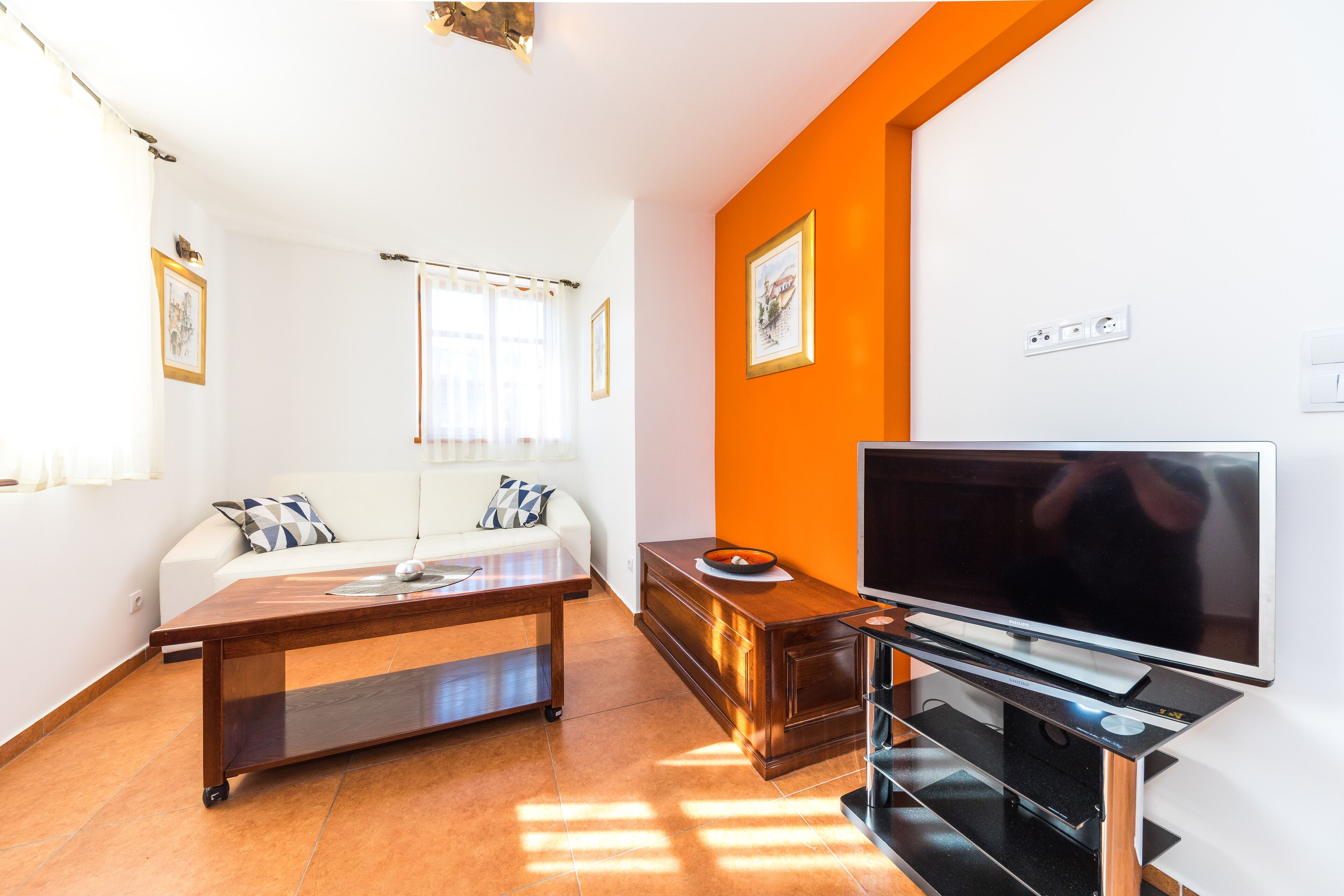 Een moderne woonkamer met een bank, salontafel, tv-meubel en kunstwerken aan de wanden.