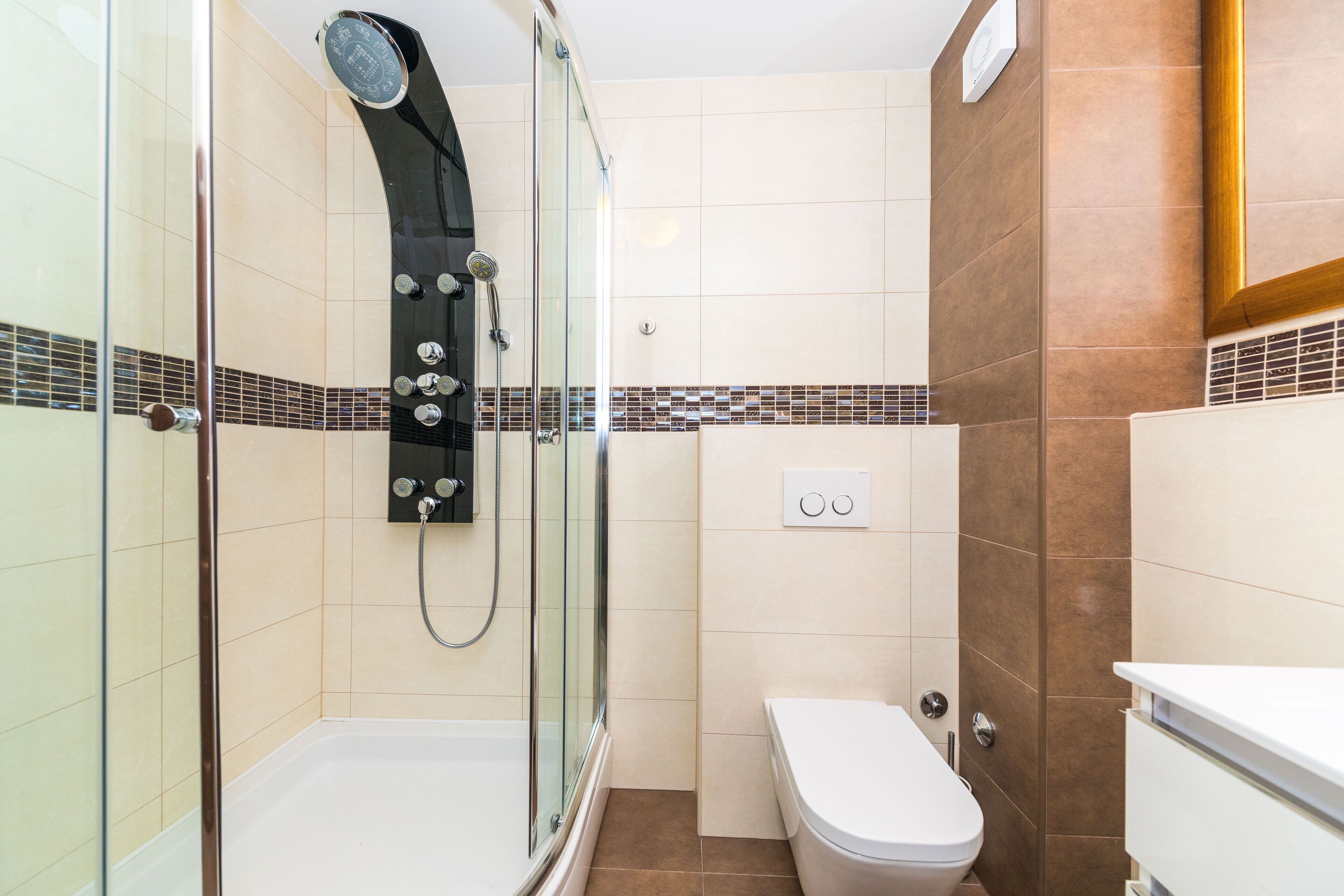 A modern bathroom with a glass-enclosed shower, a white toilet, and a sink.