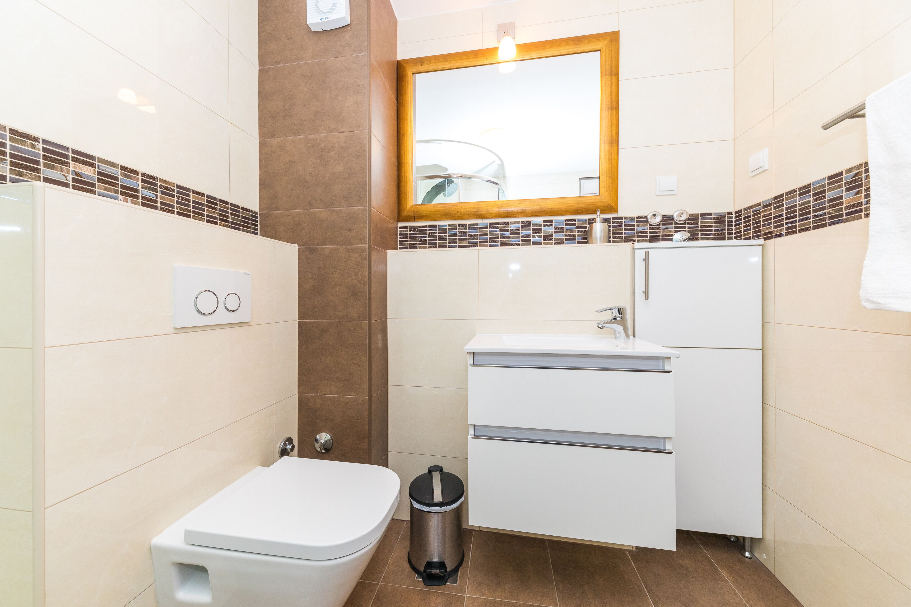 A compact bathroom with a toilet, sink, and a small trash bin.