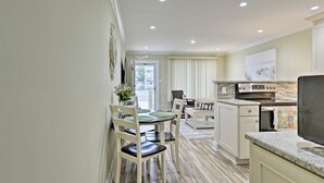 Una cocina moderna con comedor, que presenta una encimera de granito, electrodomésticos de acero inoxidable y vistas al exterior.