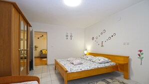 A bedroom with a wooden bed, a bedside table, a nightstand, a wardrobe, and a bathroom visible through an open door. - Apartment 2042/31807 (Istria - Pula), 5000m from the beach (Pula)