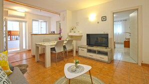 A living room with a TV, a dining table, chairs, and a sofa. - Apartment 2042/31807 (Istria - Pula), 5000m from the beach (Pula)