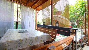 A covered outdoor seating area with a table and bench, surrounded by wooden beams and bamboo blinds. - Apartment 2042/31807 (Istria - Pula), 5000m from the beach (Pula)