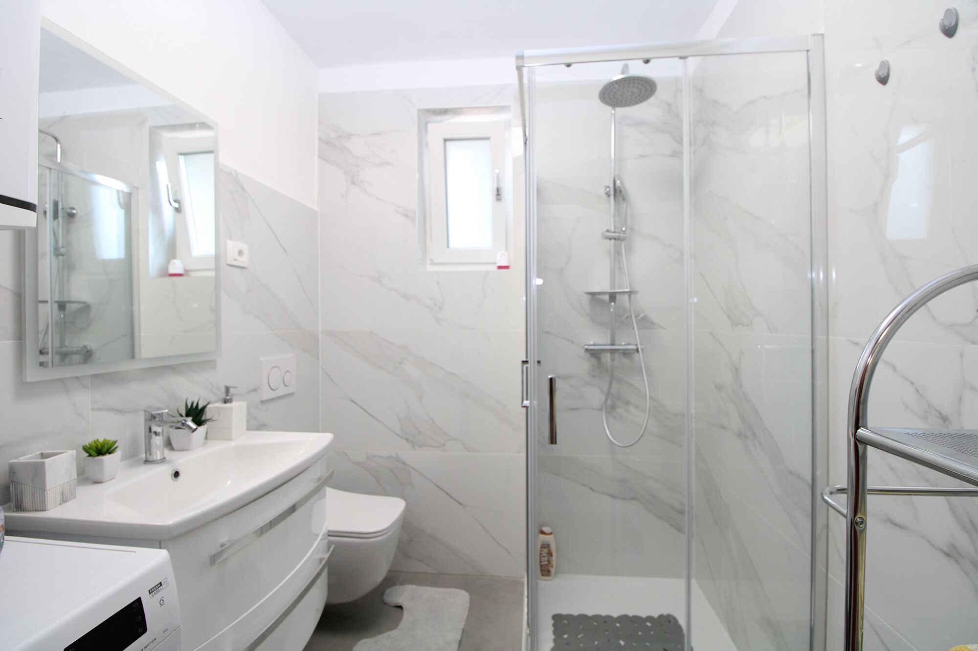 A modern bathroom with a glass-enclosed shower, a white sink, and a toilet.