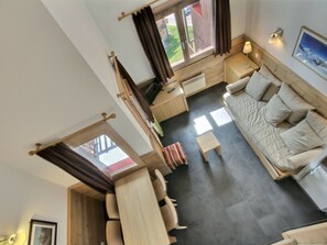A room with a sofa, a small table, a chair, a window, and a door.