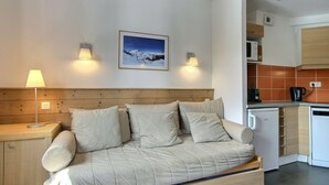 Et moderne værelse med sofa, lampe, et billede på væggen og et tekøkken.