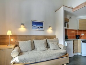 Ein modernes Zimmer mit einer Couch, einer Lampe, einem Bild an der Wand und einer Küchenzeile.