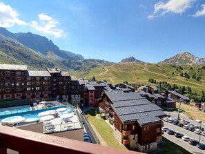 A hotel with a pool, multiple buildings, and a mountainous backdrop.