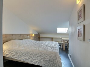 Een slaapkamer met een bed, een bureau en een dakraam.