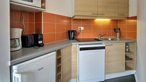 A compact kitchen with a microwave, toaster, coffee maker, and dishwasher.