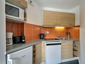 A compact kitchen with a microwave, toaster, coffee maker, and dishwasher.
