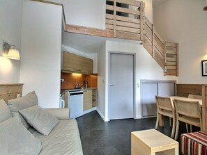Ein kompakter Wohnraum mit Küchenzeile, Essbereich und einer Treppe.