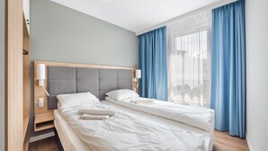 Ein Hotelzimmer mit einem Bett, Nachttischen und einem Fenster mit Vorhängen.