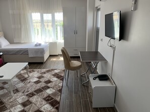 Une chambre d’hôtel avec un lit, un bureau, une chaise, une télévision et un tapis à motifs.