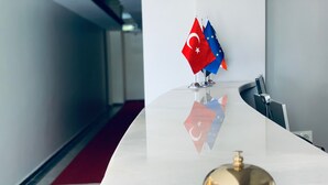 A reception desk with a gold bell, a red and blue flag, and a reflection of the flag on the wall. - Marida Hotel - Dargeçit (Dargeçit)