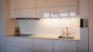 A modern kitchen with a built-in stove, a sink, and a potted plant.