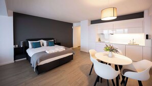 A modern bedroom with a bed, bedside tables, and a small dining area with a table and chairs.