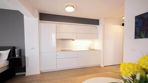 A modern kitchen with white cabinets, a central island, and a dining area with a white table and yellow flowers.