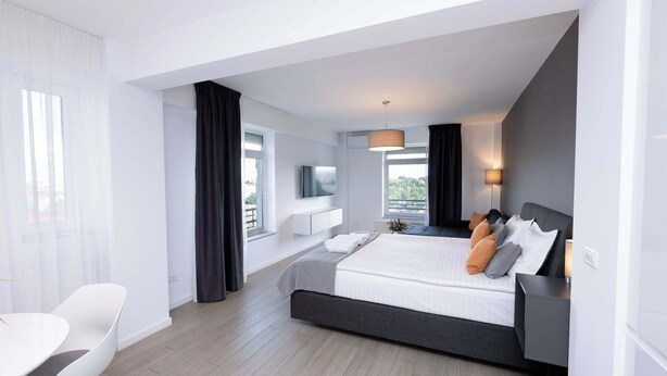 A modern hotel room with a large bed, a desk, and a TV.