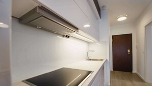 A modern kitchen with a built-in stovetop, under-cabinet lighting, and a wooden floor.