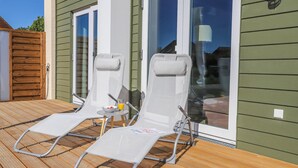 Eine Terrasse mit zwei Liegestühlen, einem kleinen Tisch und einem Glas Orangensaft.
