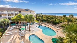 A resort with a pool area, lounge chairs, and a view of the beach.