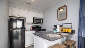 A modern kitchen with white cabinets, stainless steel appliances, a granite countertop, and a small island with stools.