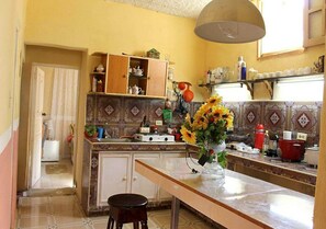 A kitchen with a central island, a wooden cabinet, and a hanging light fixture. - Hostal La Casa Roja TRINIDAD (Trinidad)