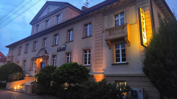 Ein Hotel mit einer klassischen Fassade, einer gut sichtbaren Schilderung und einem gut beleuchteten Eingang.