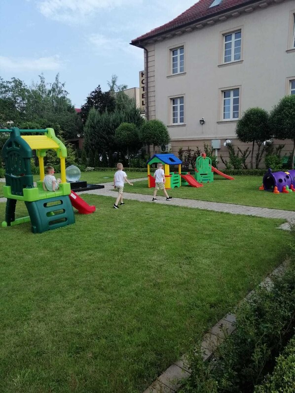 A hotel with a playground in the courtyard, including slides and climbing structures. - Hotel Libero (Milicz)
