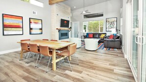 Un vaste espace de vie comprenant une table à manger en bois, des sièges modernes et une cheminée.