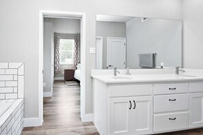 A modern bathroom with a double sink vanity, a large mirror, and a walk-in closet.