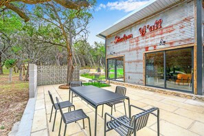 Un restaurant doté d’une terrasse, d’une façade en métal ondulé et offrant une vue sur les arbres environnants.