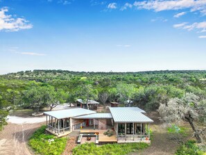 Une maison moderne dotée d’une grande terrasse, d’un patio couvert et offrant une vue sur une forêt dense.