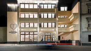 A multi-story building with a modern design, featuring a prominent entrance with glass doors and a staircase leading to the upper floors. - W Sercu Krakowa Aparthotel (Kraków)