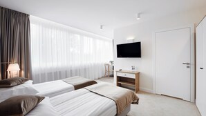 A hotel room with two beds, a desk, a TV, and a door. - W Sercu Krakowa Aparthotel (Kraków)