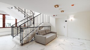 A modern interior with a staircase, a sofa, and a marble floor. - W Sercu Krakowa Aparthotel (Kraków)