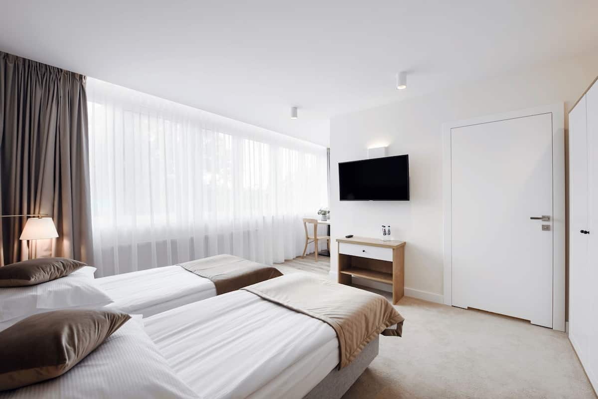Een hotelkamer met twee bedden, een televisie, een bureau en een kledingkast.