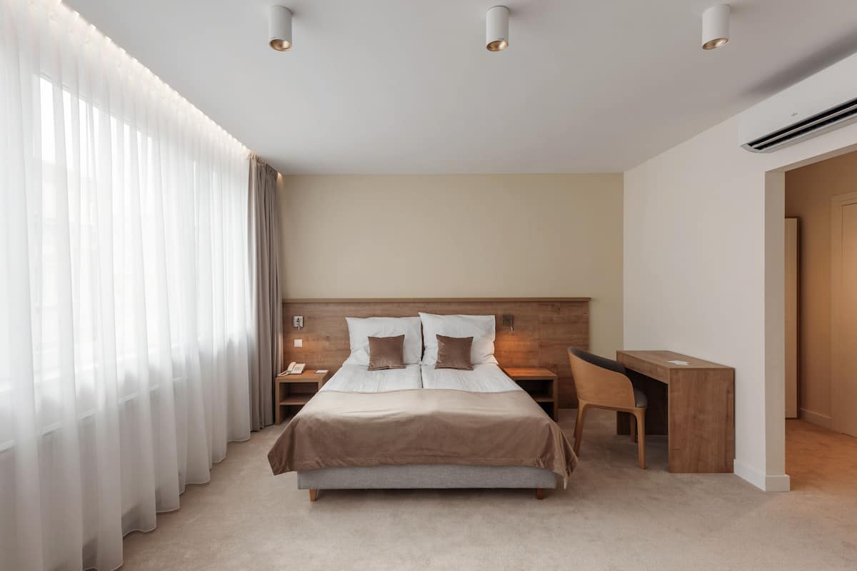 Een hotelkamer met een bed, nachtkastjes, een bureau en een kledingkast.