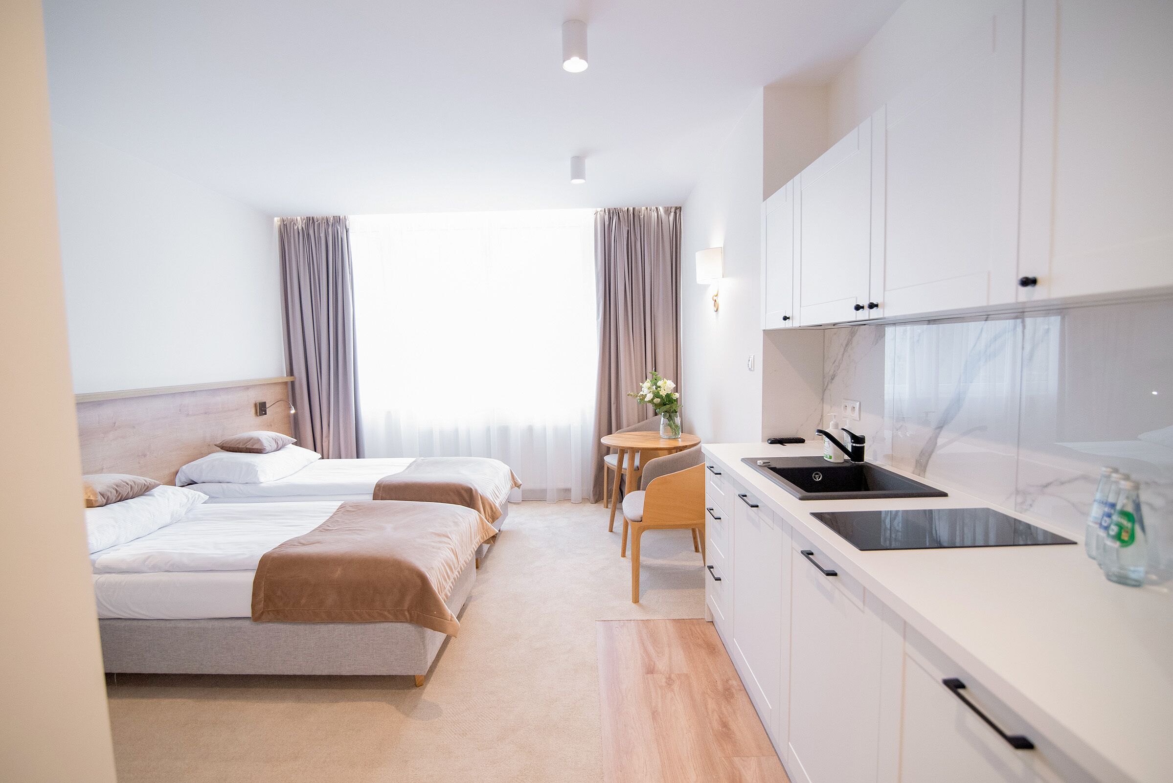 Une chambre d’hôtel avec deux lits, une petite cuisine équipée d’un évier et un coin repas.