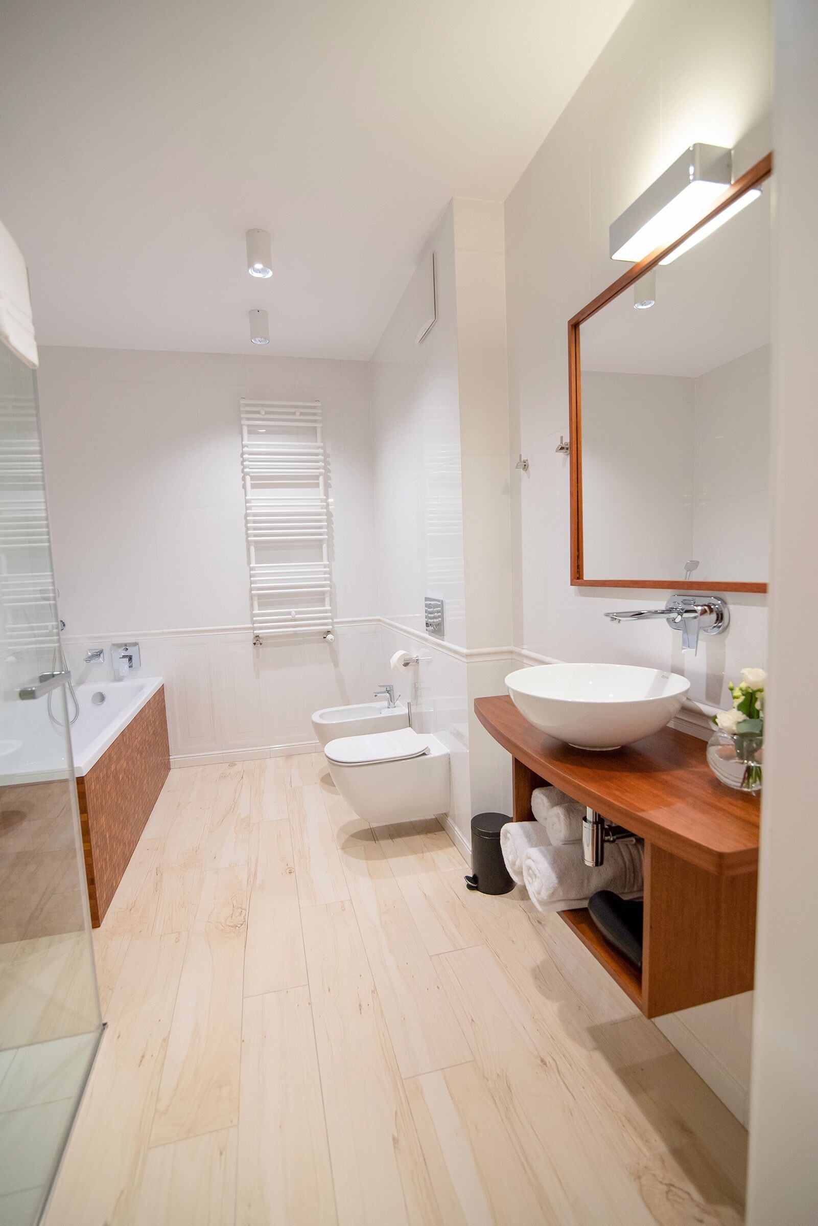 Un baño moderno con un lavabo grande de color blanco, un mueble de tocador de madera, un espejo y una zona de ducha.