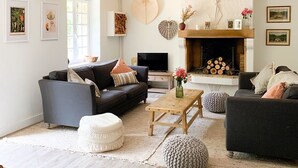 A spacious living room with a fireplace, a sofa set, and a television. - House in Perche (Marolles-les-Braults)