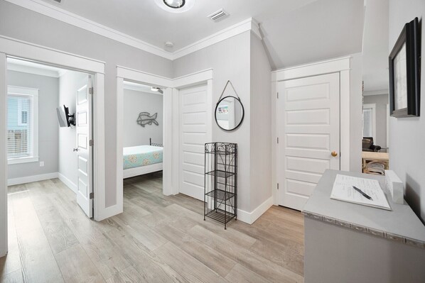 A modern, well-lit room with a bed, a desk with a mirror, and a small shelf with books. - Walk to the Beach | Luxe 4BR Home with Pool + Golf Cart (Panama City Beach)