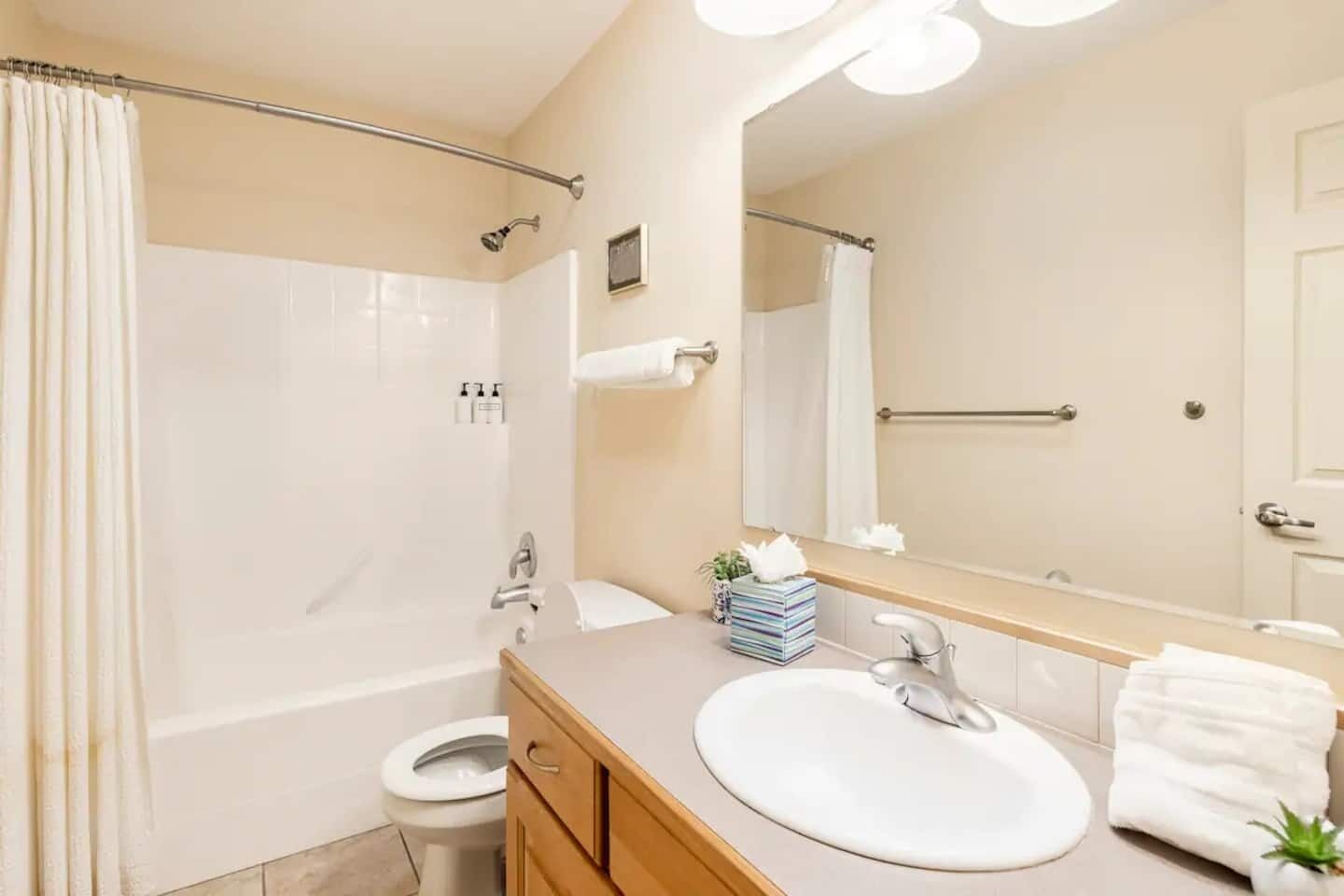 A modern bathroom with a bathtub, toilet, sink, and a large mirror.