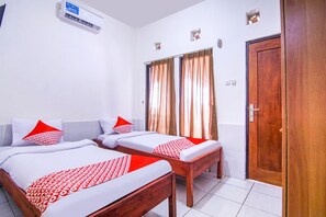 A hotel room with two beds, a wooden door, and an air conditioning unit. - OYO 3317 Maju Jaya Homestay (Bogor)