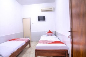 A small, clean room with two single beds, a television, and an air conditioning unit on the wall. - OYO 3317 Maju Jaya Homestay (Bogor)