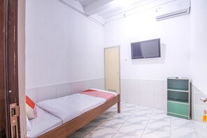 A single bed with a red and white patterned bedspread, a television mounted on the wall, a green storage unit, and a white tiled floor. - OYO 3317 Maju Jaya Homestay (Bogor)